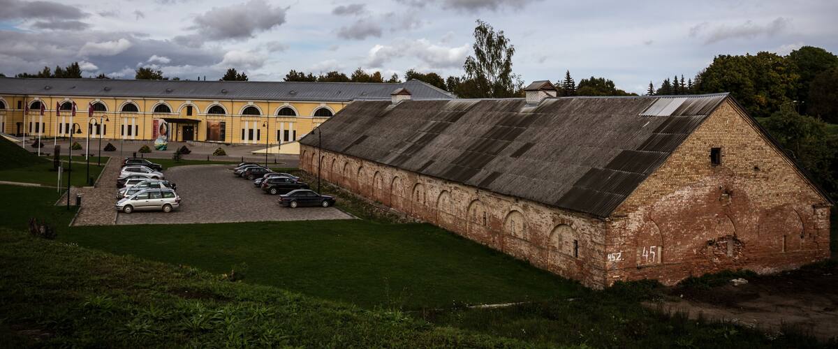 Ein großes, historisches Gebäude mit Parkplatz und einer Rasenfläche davor.