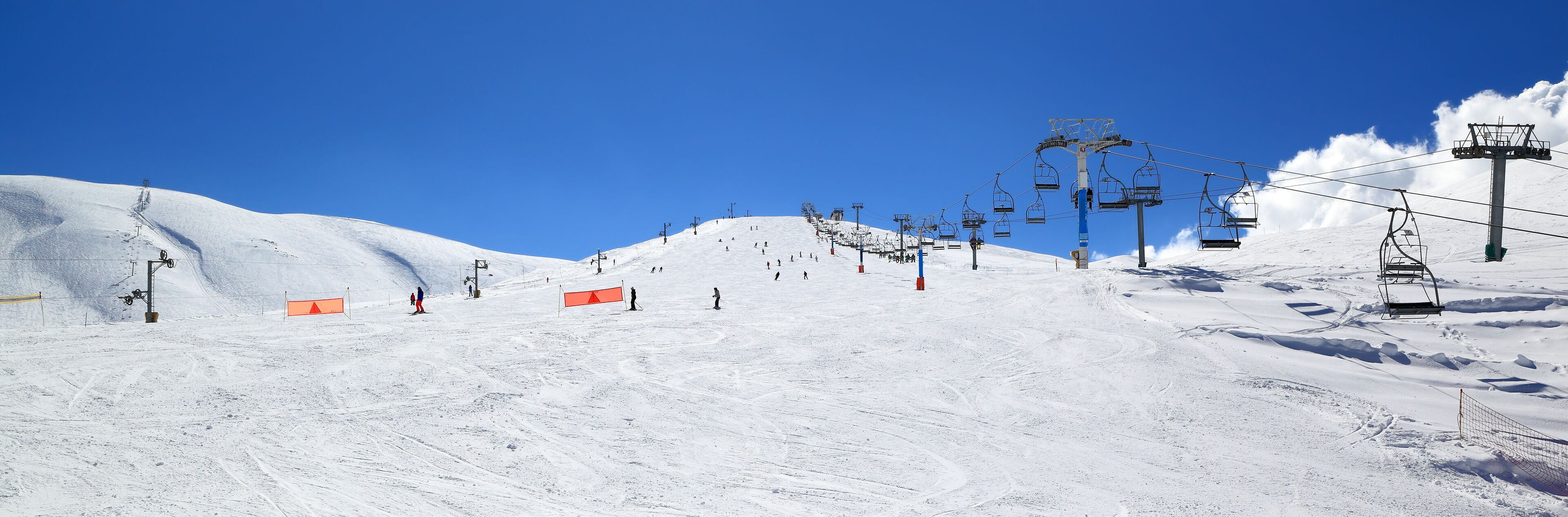 A snowy ski slope with ski lifts and skiers.