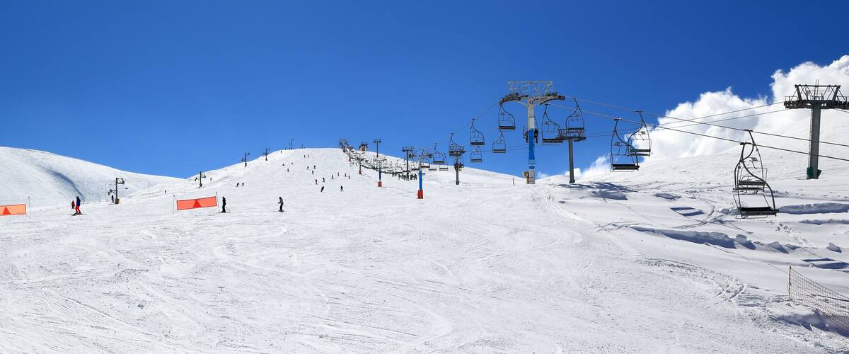 A snowy ski slope with ski lifts and skiers.