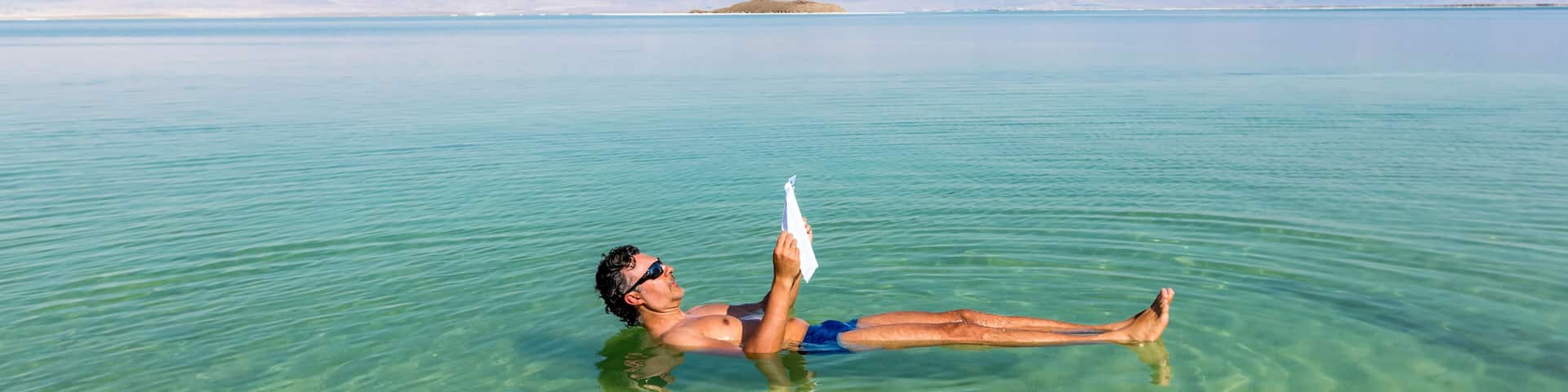 Man relaxing in nature.. View of Dead Sea coastline. Salt crystals at sunset. Texture of Dead sea. Salty sea shore. Web banner in panoramic view.