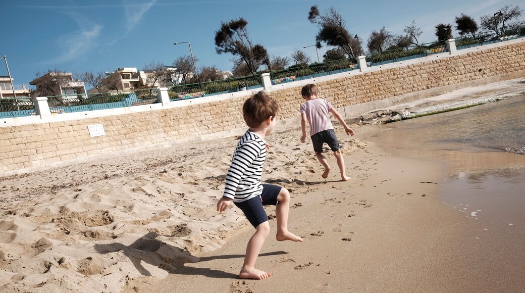 Two young boys running and playing at the beach in St. Thomas Bay, Malta.