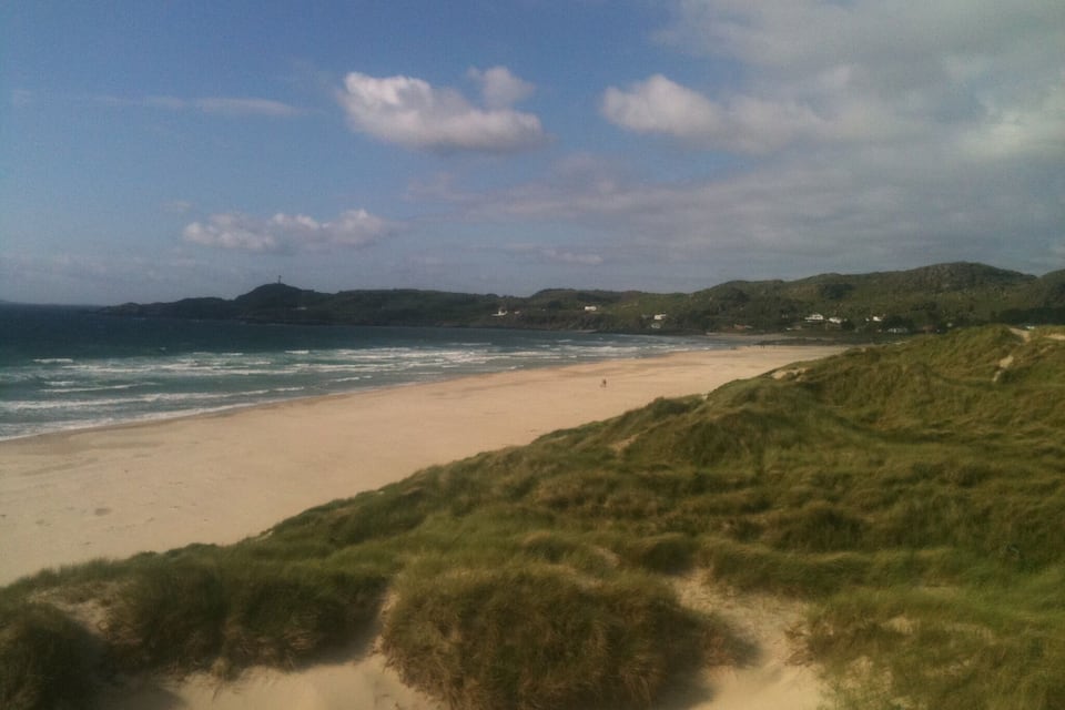 Una platja amb dunes de sorra i una línia de costa.