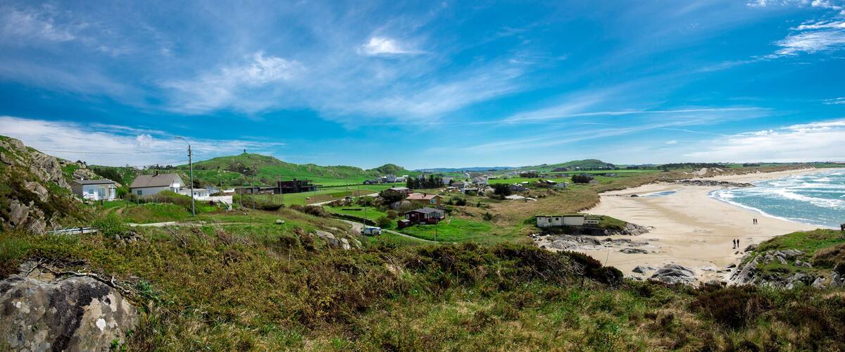 Panoramic view of a long Hellestostranden sand beach and surrounding area with green hills and fields near Stavanger city, Norway, May 2018