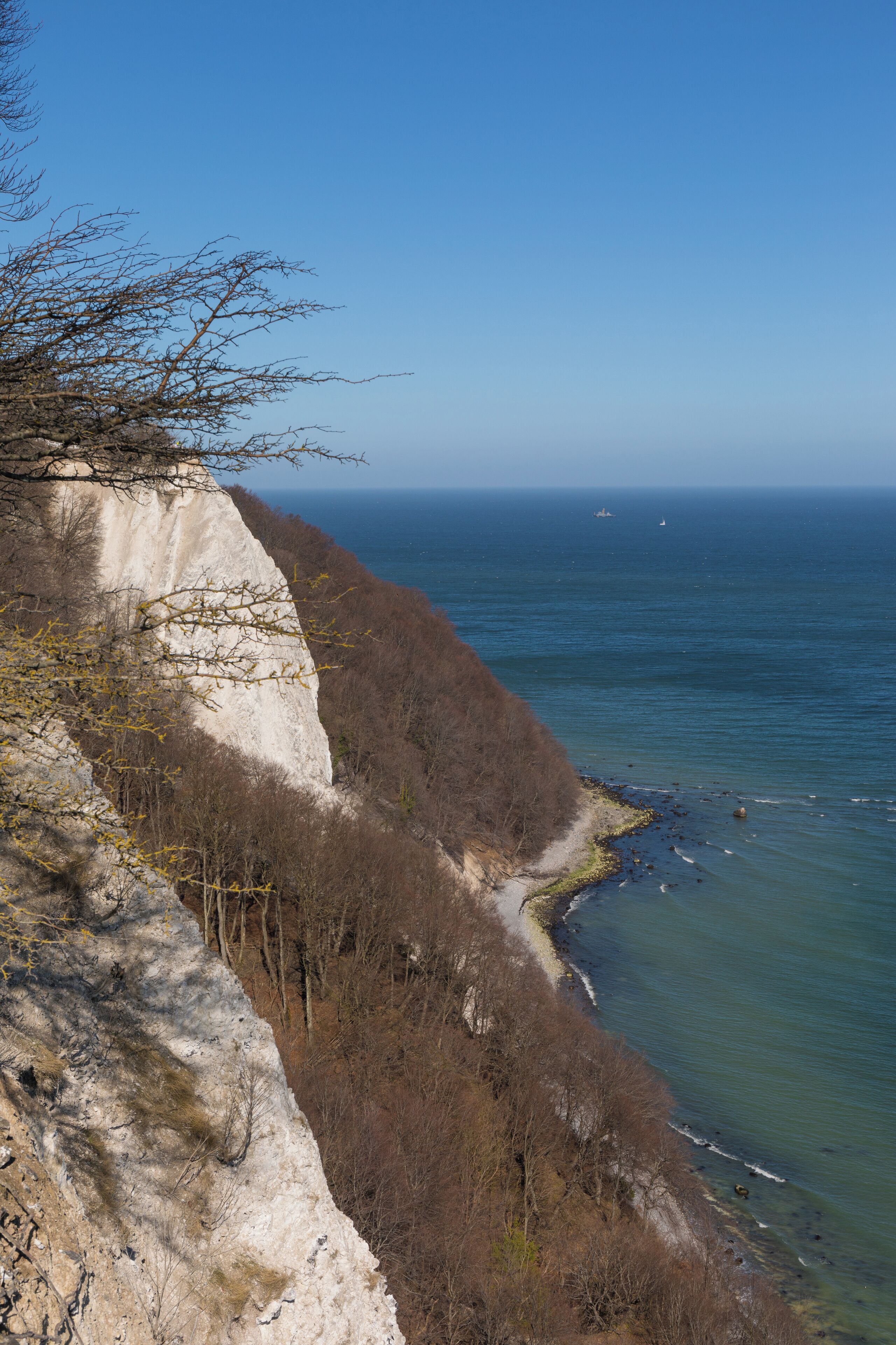 A coastal cliff with a rocky shoreline and sparse vegetation.