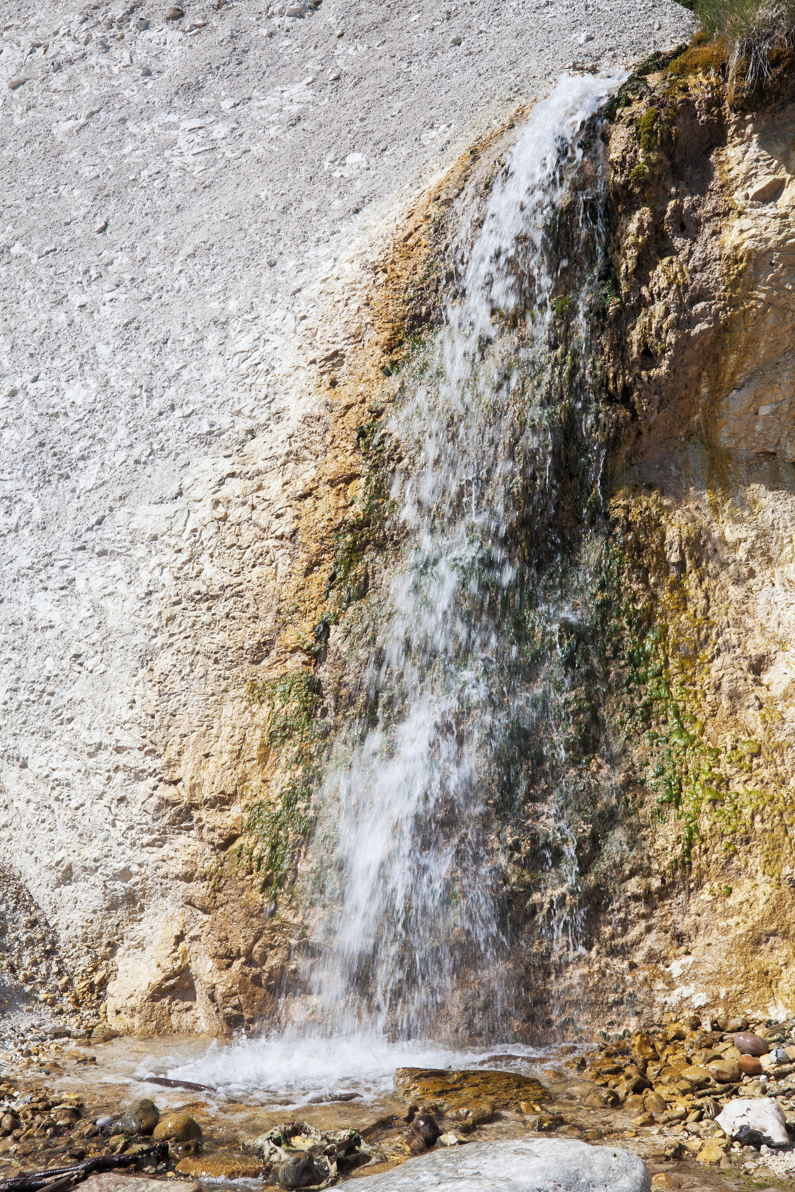 A waterfall cascading down a rocky cliff into a shallow pool.