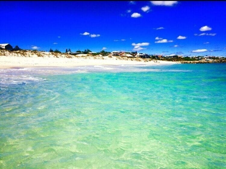 Une plage à l’eau turquoise et limpide, bordée d’un rivage sablonneux.