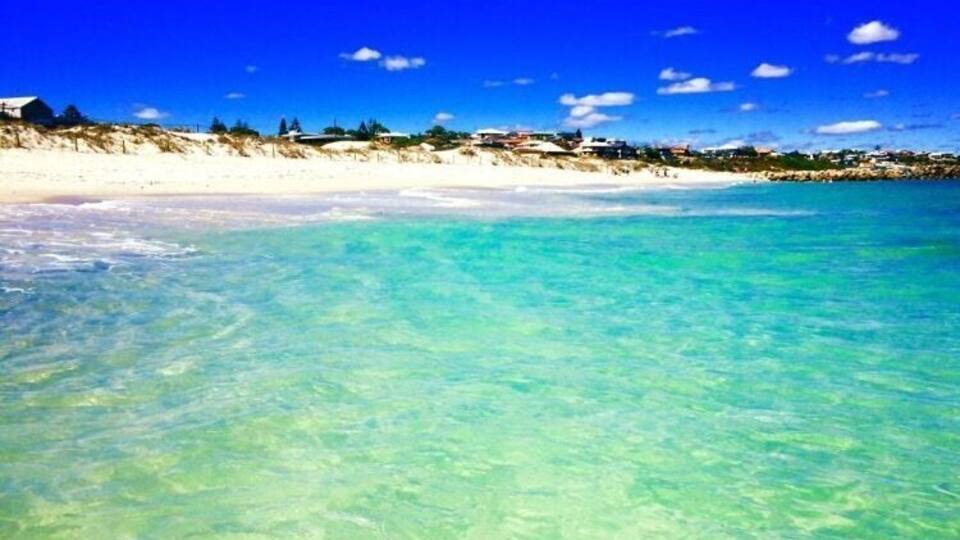 Une plage à l’eau turquoise et limpide, bordée d’un rivage sablonneux.