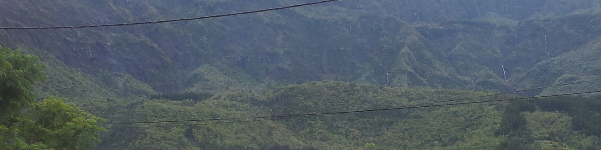 Une maison avec un toit rouge, un panneau de signalisation indiquant un arrêt obligatoire et une montagne en arrière-plan.