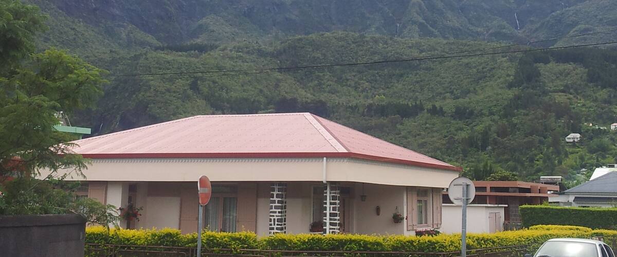 A house with a red roof, a stop sign, and a mountain in the background.