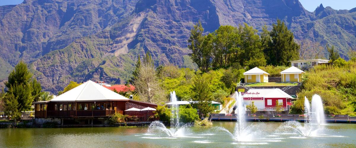 Un lac avec des fontaines, une montagne et des bâtiments.