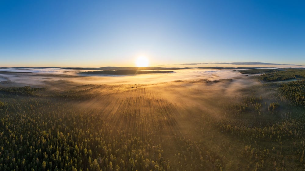 Sonnenaufgang über von Bodennebel bedecktem See und Wäldern in Lappland, Västerbotten, Schweden