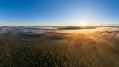 Sonnenaufgang über von Bodennebel bedecktem See und Wäldern in Lappland, Västerbotten, Schweden