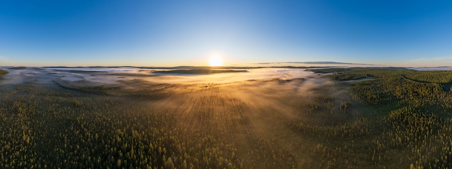 Sonnenaufgang über von Bodennebel bedecktem See und Wäldern in Lappland, Västerbotten, Schweden