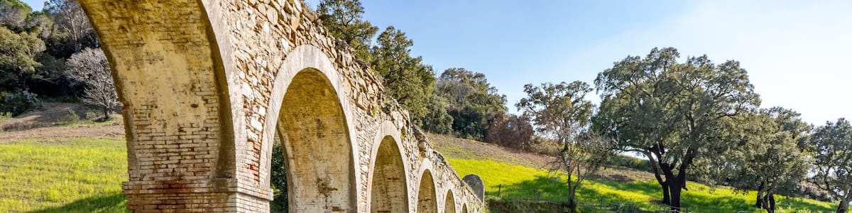 A series of stone arches in a grassy field with a clear sky.