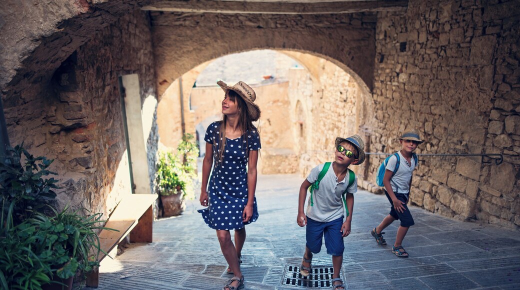 Kids tourists sightseeing beautiful Italian town of Campiglia Marittima. Sunny summer day. Italy, Tuscany.Kids are walking charming streets and archways.Nikon D810