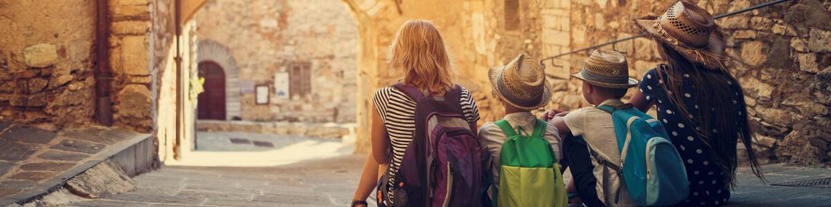 Mother and kids tourists sightseeing beautiful Italian town of Campiglia Marittima. Sunny summer day. Italy, Tuscany.