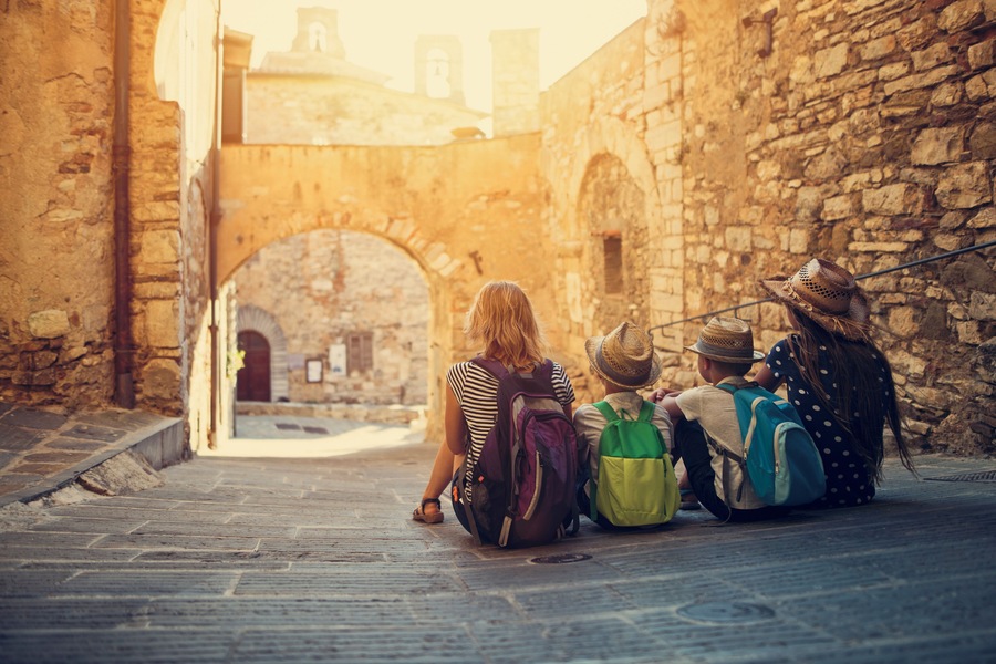 Mother and kids tourists sightseeing beautiful Italian town of Campiglia Marittima. Sunny summer day. Italy, Tuscany.