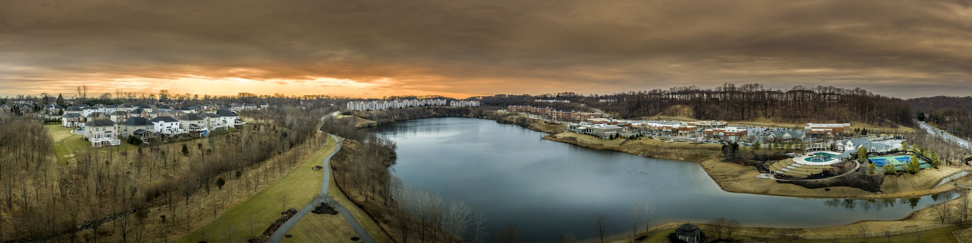 Aerial panorama of American luxury real estate neighborhood in Pikesville Maryland with single family houses, mansions, high quality buildings, condos, town houses and shop around a former quarry lake