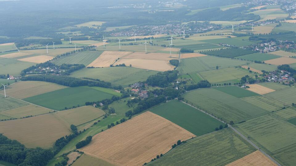 An aerial view of a rural landscape with wind turbines and fields.
