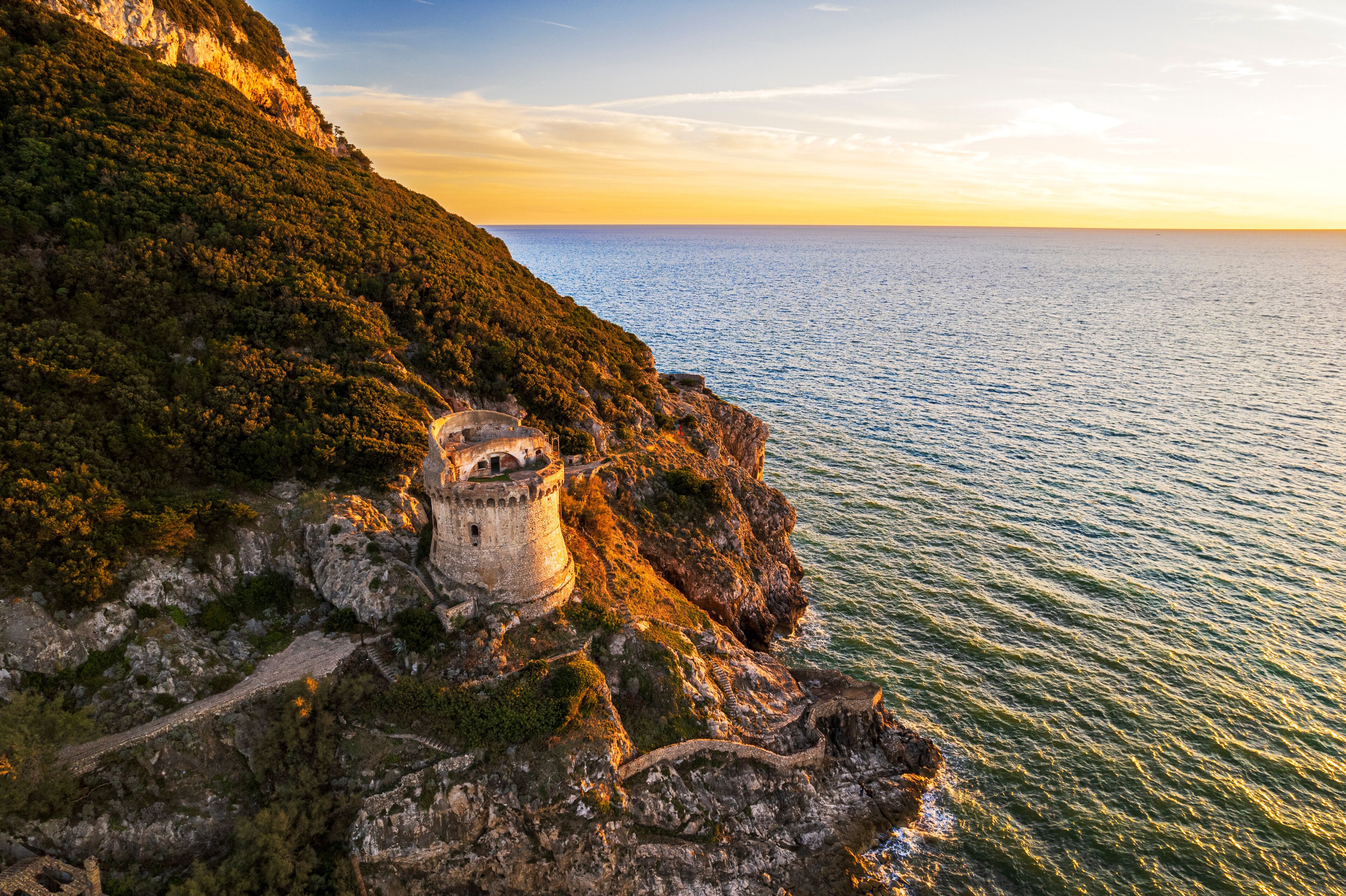 Medieval round tower standing on top of a cliff facing the sea at sunset, aerial shot, Sabaudia, Circeo National Park, Latina province, Latium, Lazio, Italy