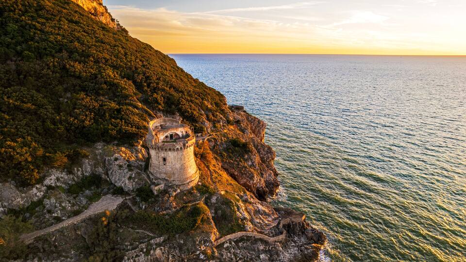 A coastal cliff with a historic tower and a clear view of the sea.