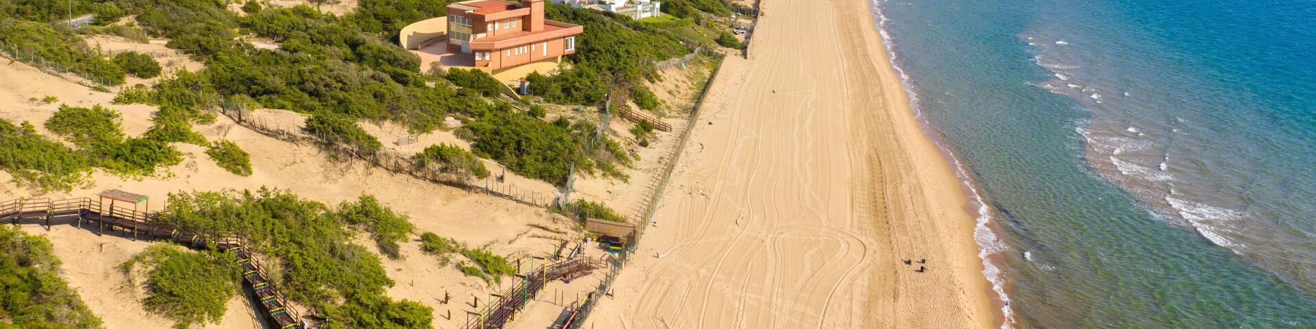 Aerial view of the seafront of Sabaudia, Italy. The beach is almost empty. In the background the Circeo promontory.