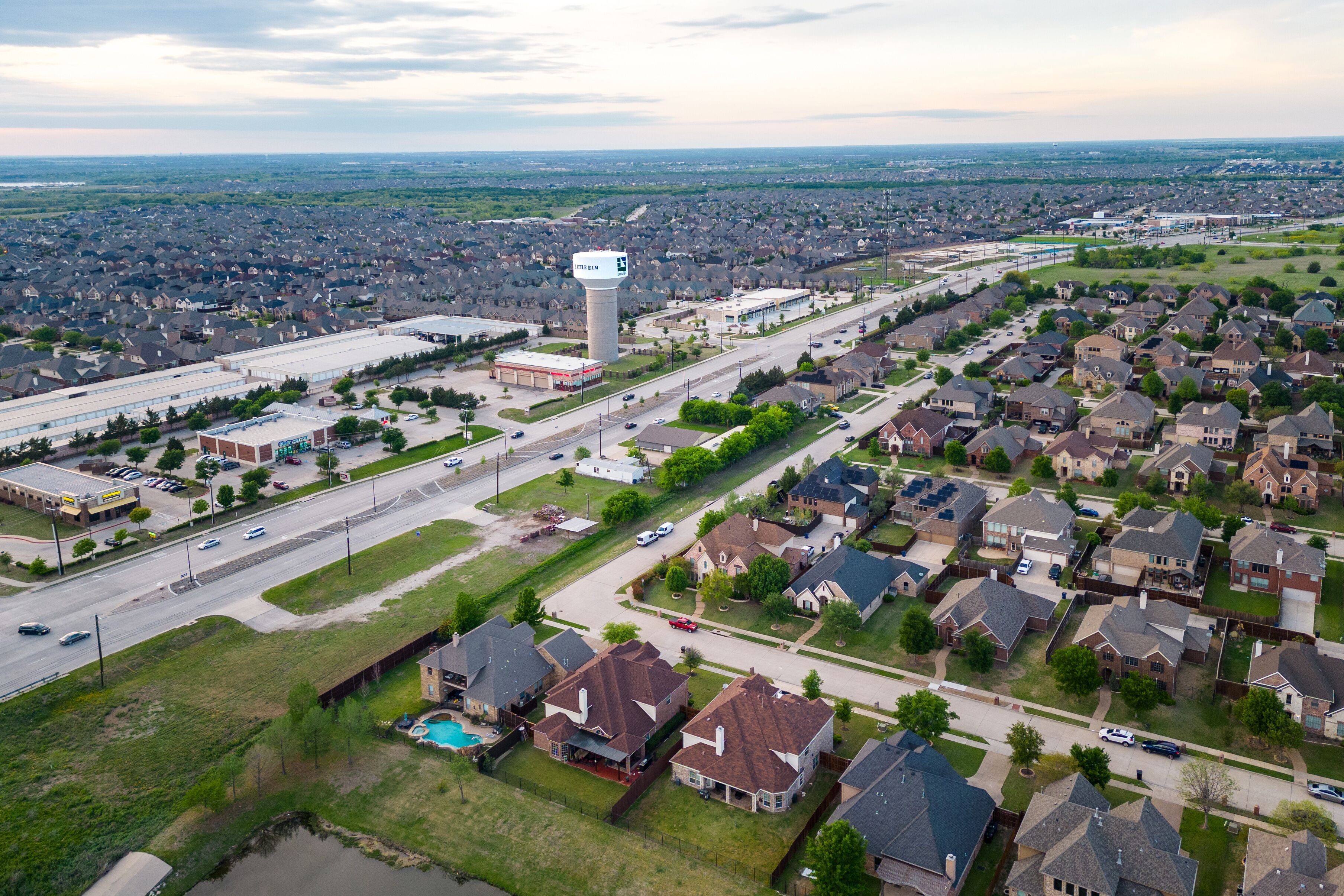 Aerial view of suburban neighborhood with houses roads commercial buildings and water tower