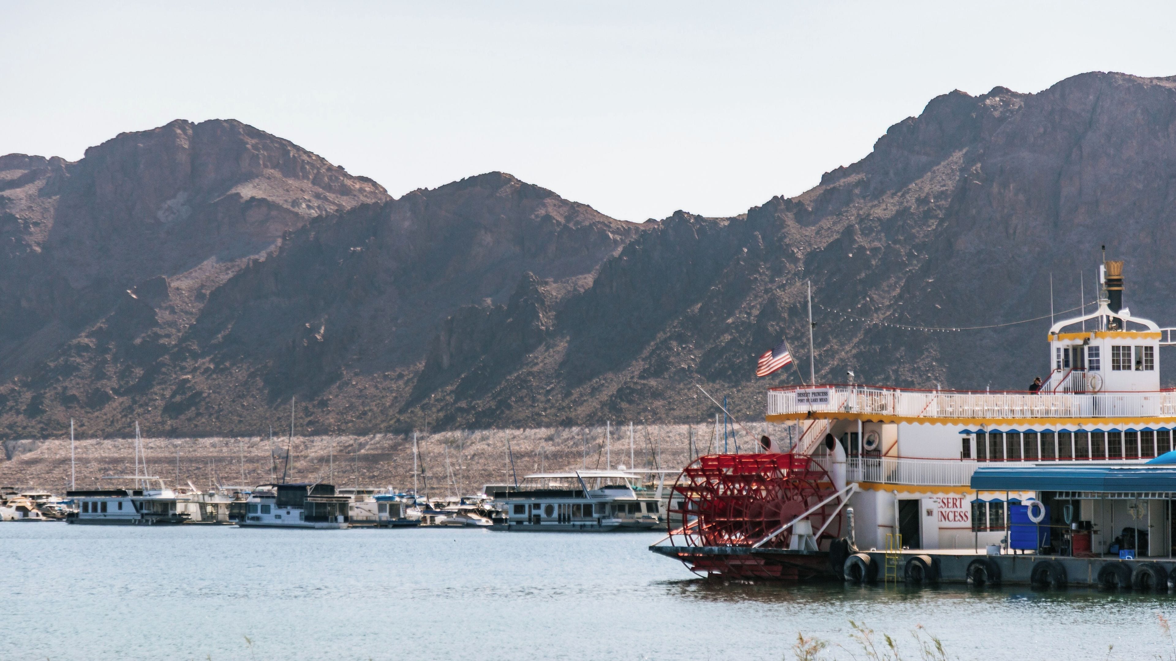 A riverboat docked at a marina with mountains in the background.