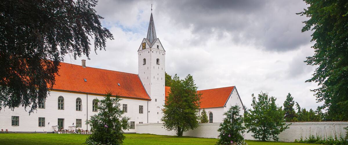 A white building with a red roof and a tall tower.