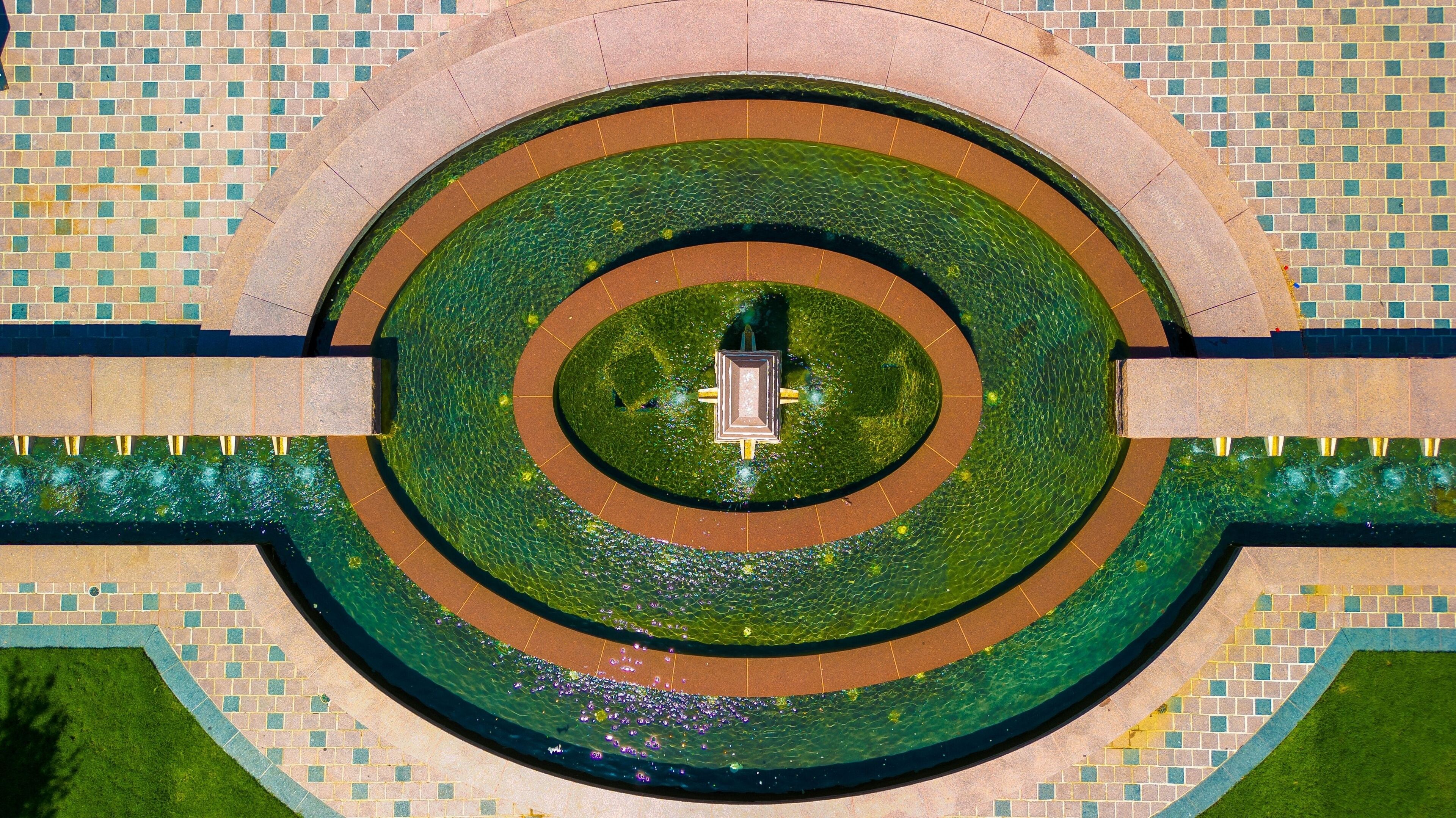 A circular water feature with a central statue, surrounded by a tiled walkway.