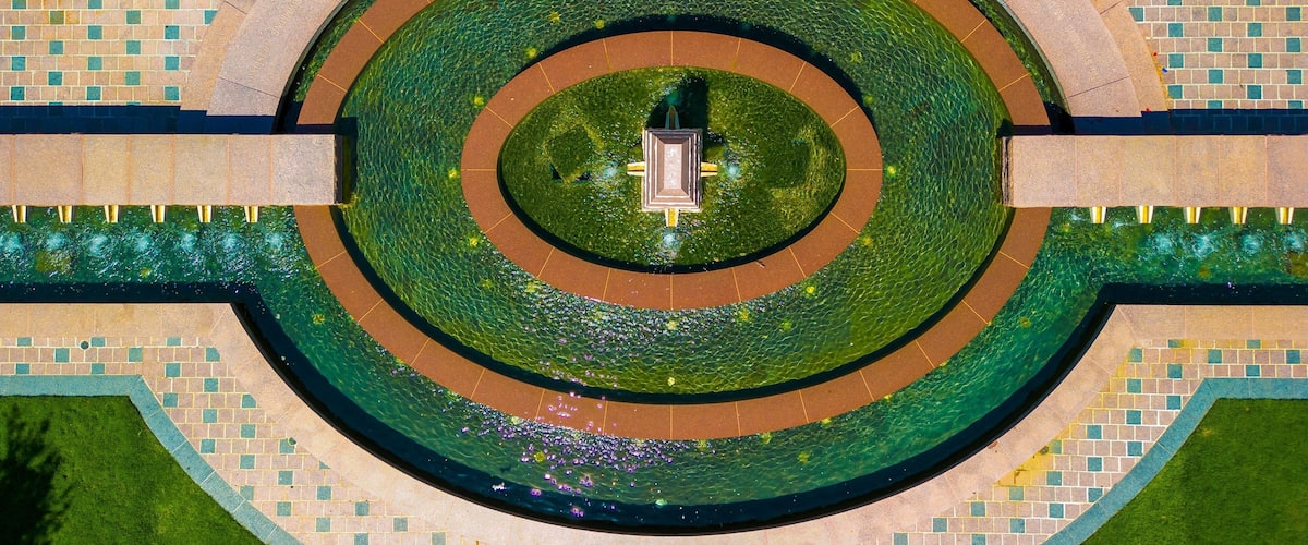 A circular water feature with a central statue, surrounded by a tiled walkway.