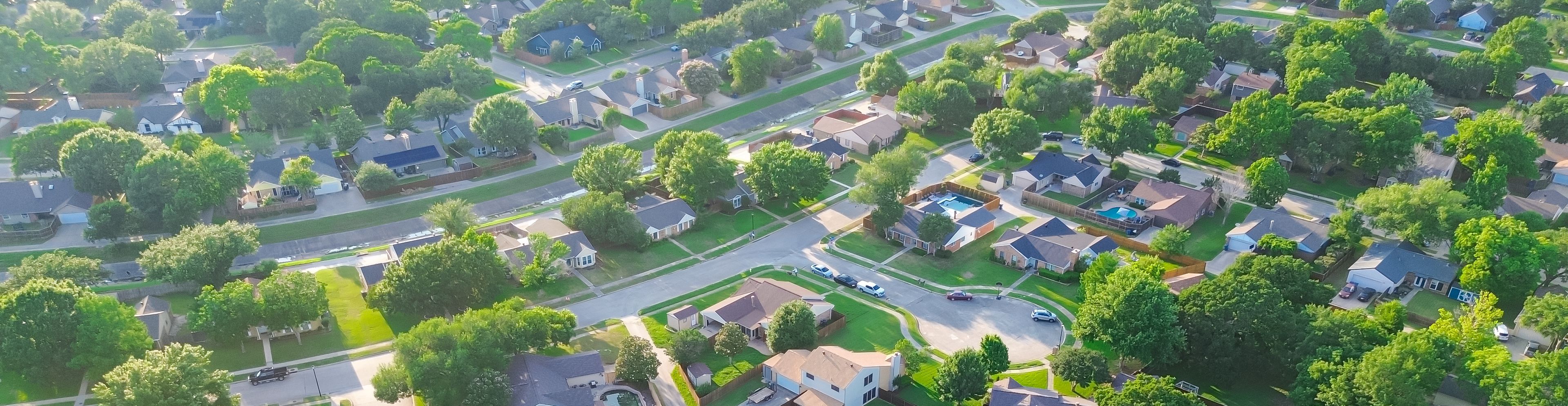 Drainage concrete channel in lush greenery residential neighborhood in Coppell Texas Dallas Fort Worth metroplex, row of detached single-family houses swimming pool, large backyard, grassy lawn