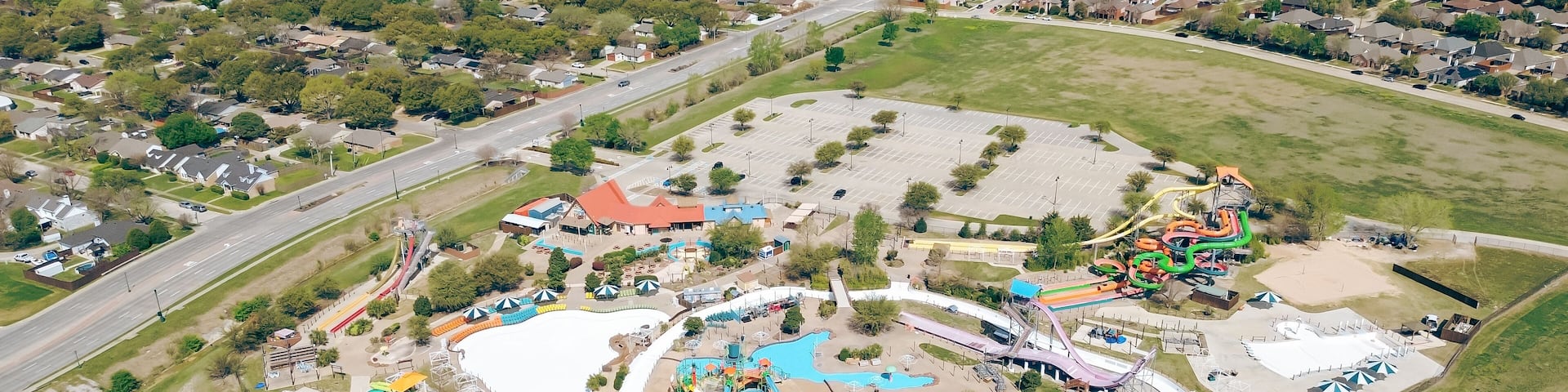 Large water park tropical theme aquatic complex near residential neighborhood of fast-growing Dallas suburbs, The Colony, Denton County, Texas, colorful slides, pools, Lewisville Lake background