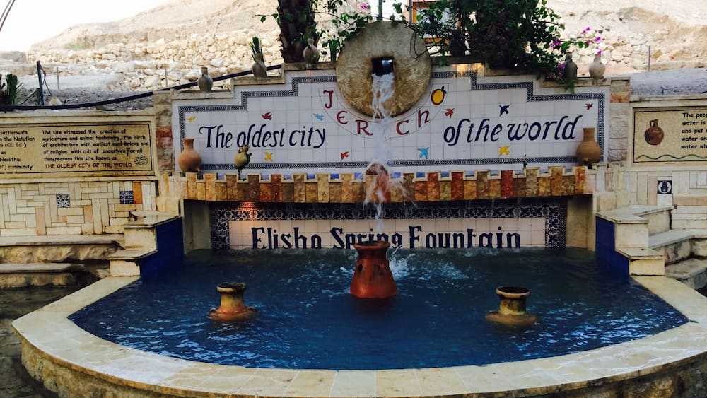 An ancient city wall with a fountain and inscriptions.