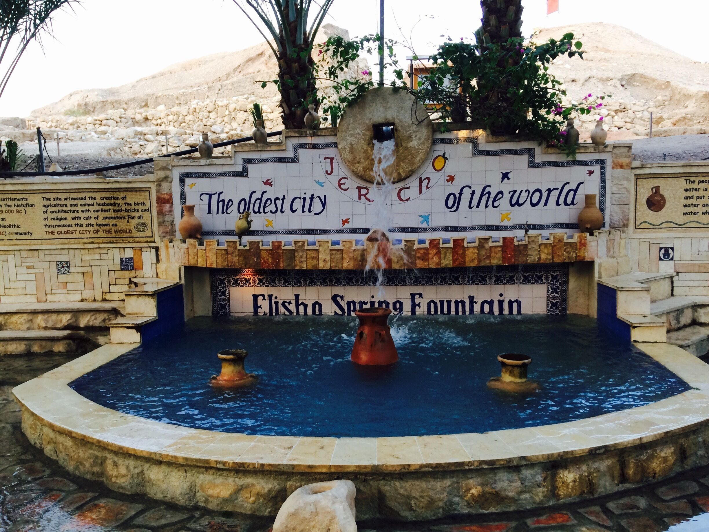 An ancient city wall with a fountain and inscriptions.