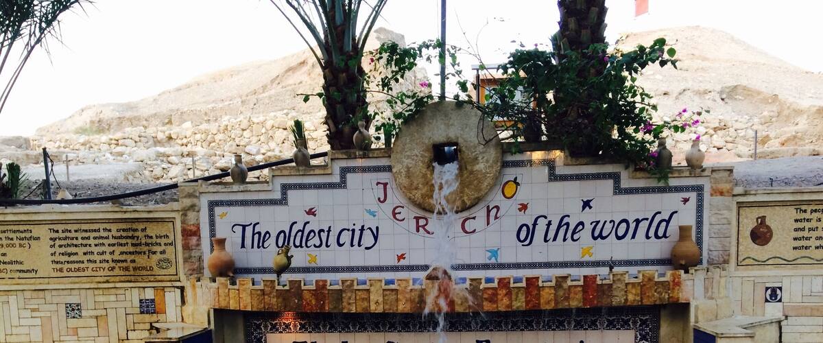 An ancient city wall with a fountain and inscriptions.