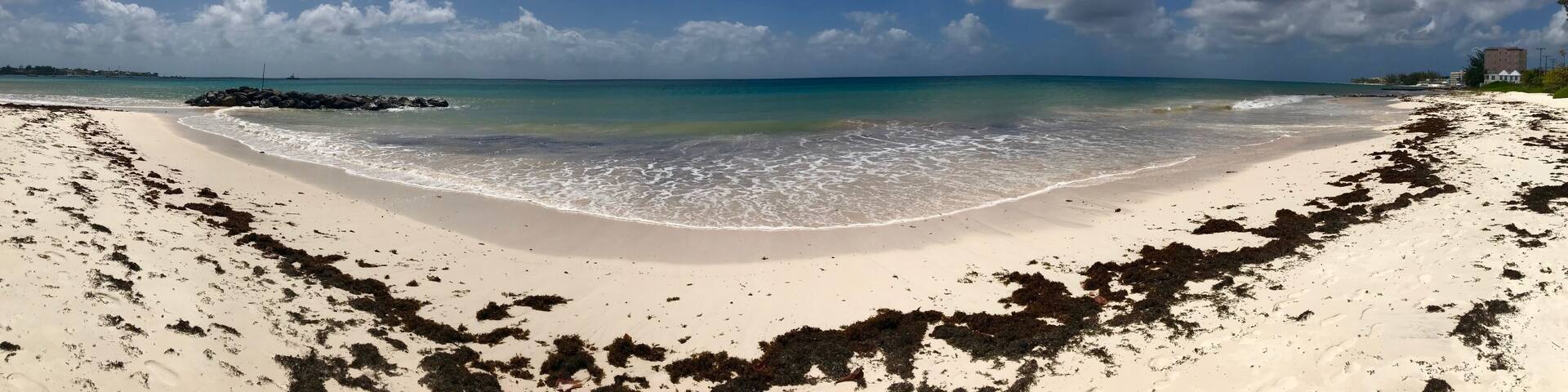 Panorama of an idyllic and beautiful beach in Barbados (Caribbean island): Nobody, white sand, turquoise water, waves and white clouds