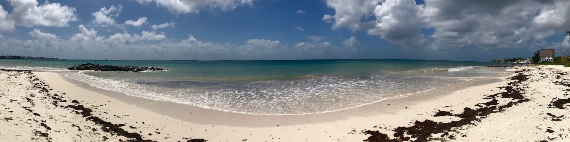 Panorama of an idyllic and beautiful beach in Barbados (Caribbean island): Nobody, white sand, turquoise water, waves and white clouds