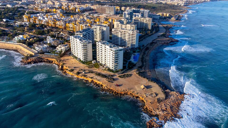 A coastal cityscape with high-rise buildings, a beach, and the ocean.