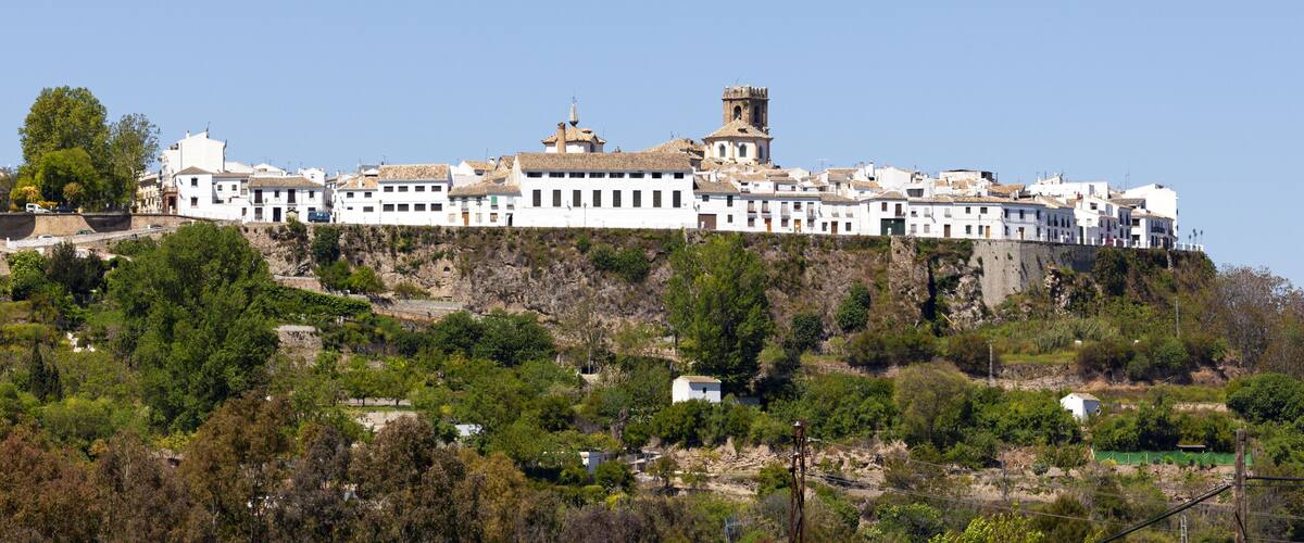 A white building complex on a hillside with a tower.
