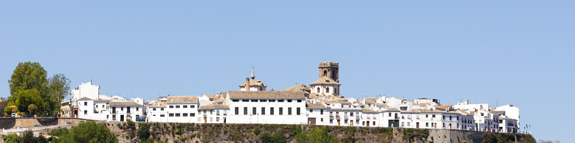 A white building complex on a hillside with a tower.
