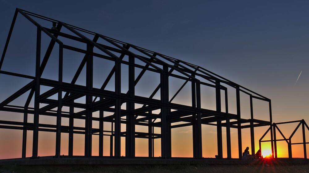 A steel framework structure silhouetted against a sunset sky.