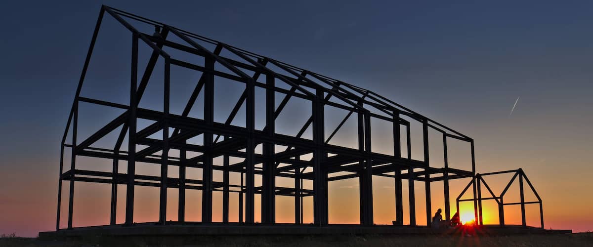 A steel framework structure silhouetted against a sunset sky.