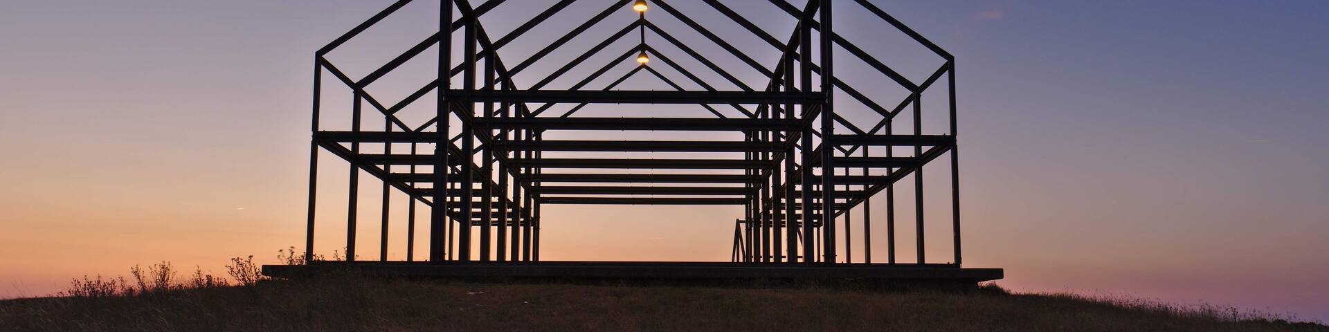 A metal framework structure silhouetted against a sunset sky.