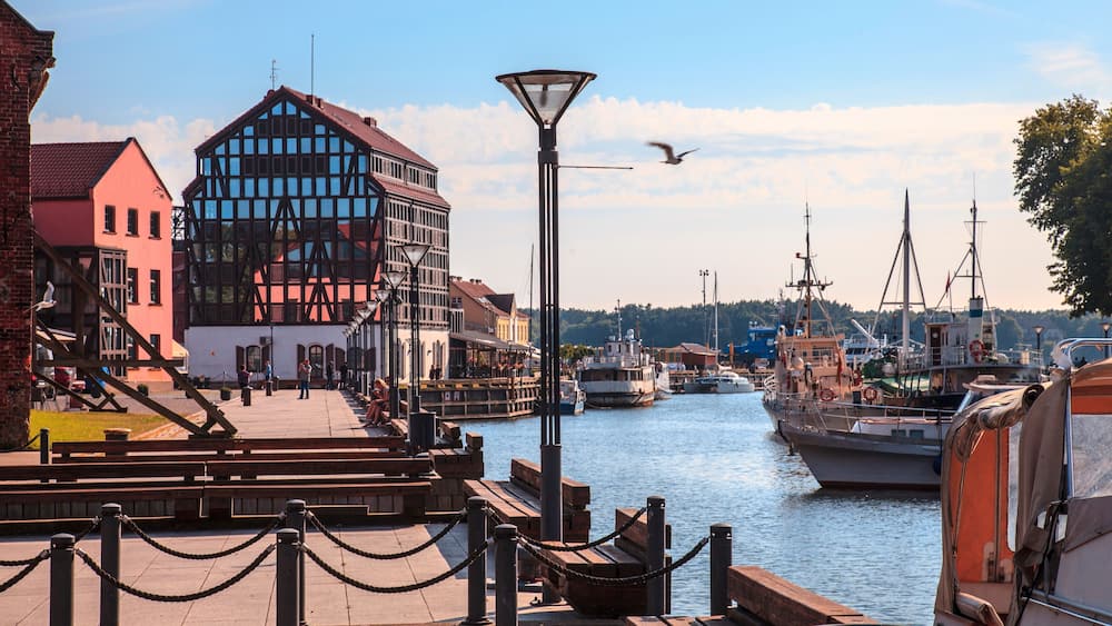 A harbor with boats, a wooden pier, and buildings along the water.
