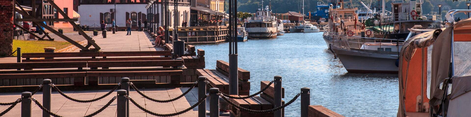 A harbor with boats, a wooden pier, and buildings along the water.