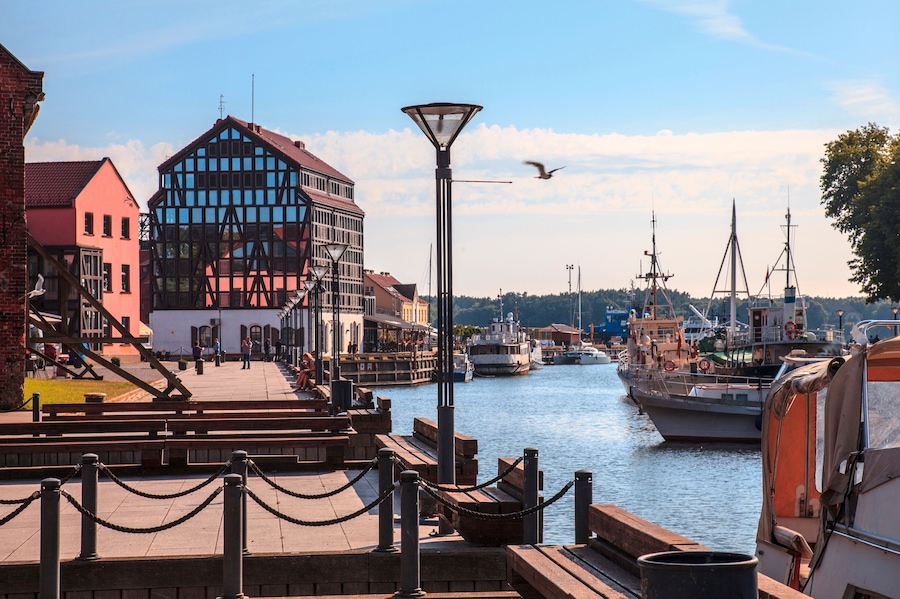 Un puerto con barcos, un muelle de madera y edificios a lo largo del agua.