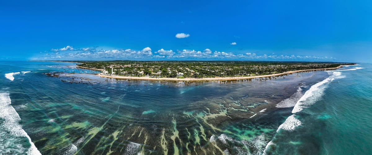 A coastal island with clear waters, a sandy beach, and a pier.