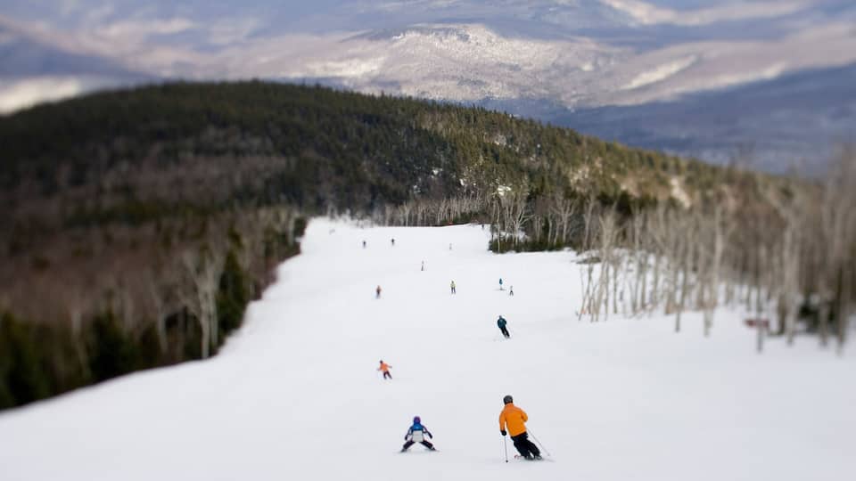 A snowy ski slope with skiers descending.