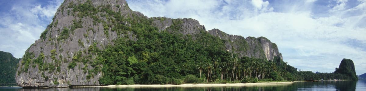A calm sea with a large island featuring a prominent peak and dense greenery.